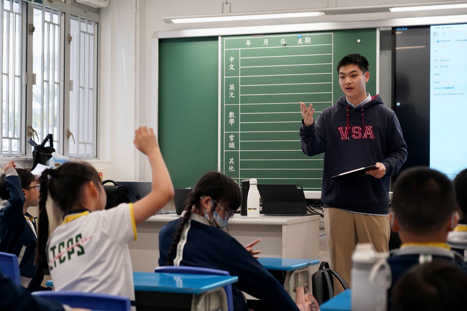A tutor leads a session at Ho Man Tin Ling To Catholic School while a pupil raises her hand to answer.