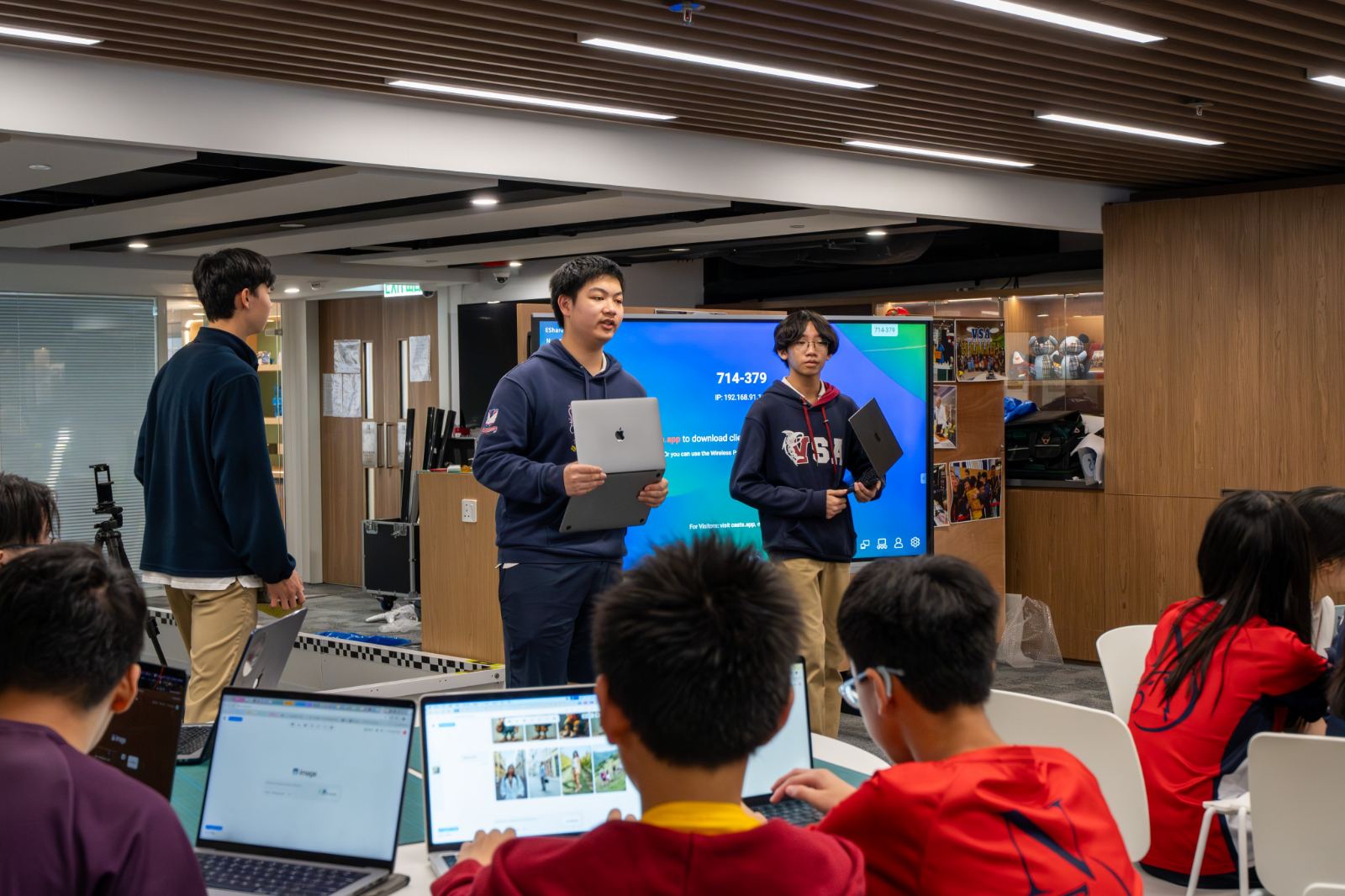 Two tutors present to students working at laptops during a 2024/25 session.