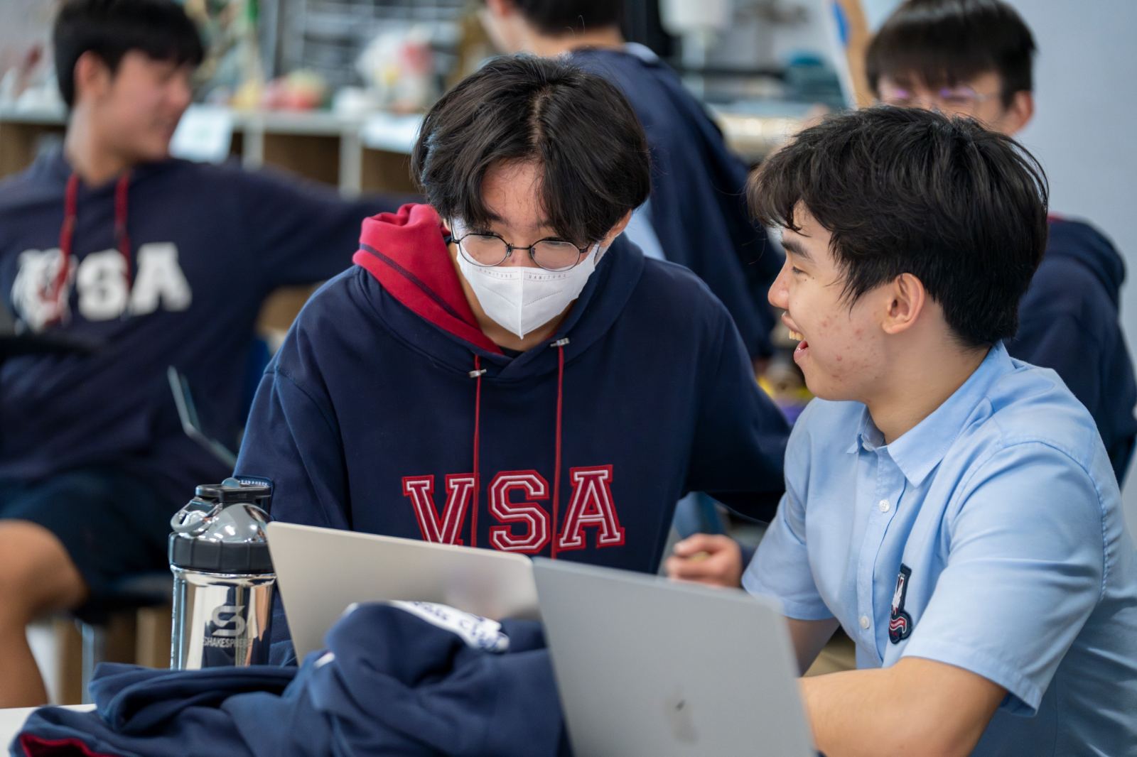 A tutor talks a student through their work at a laptop.